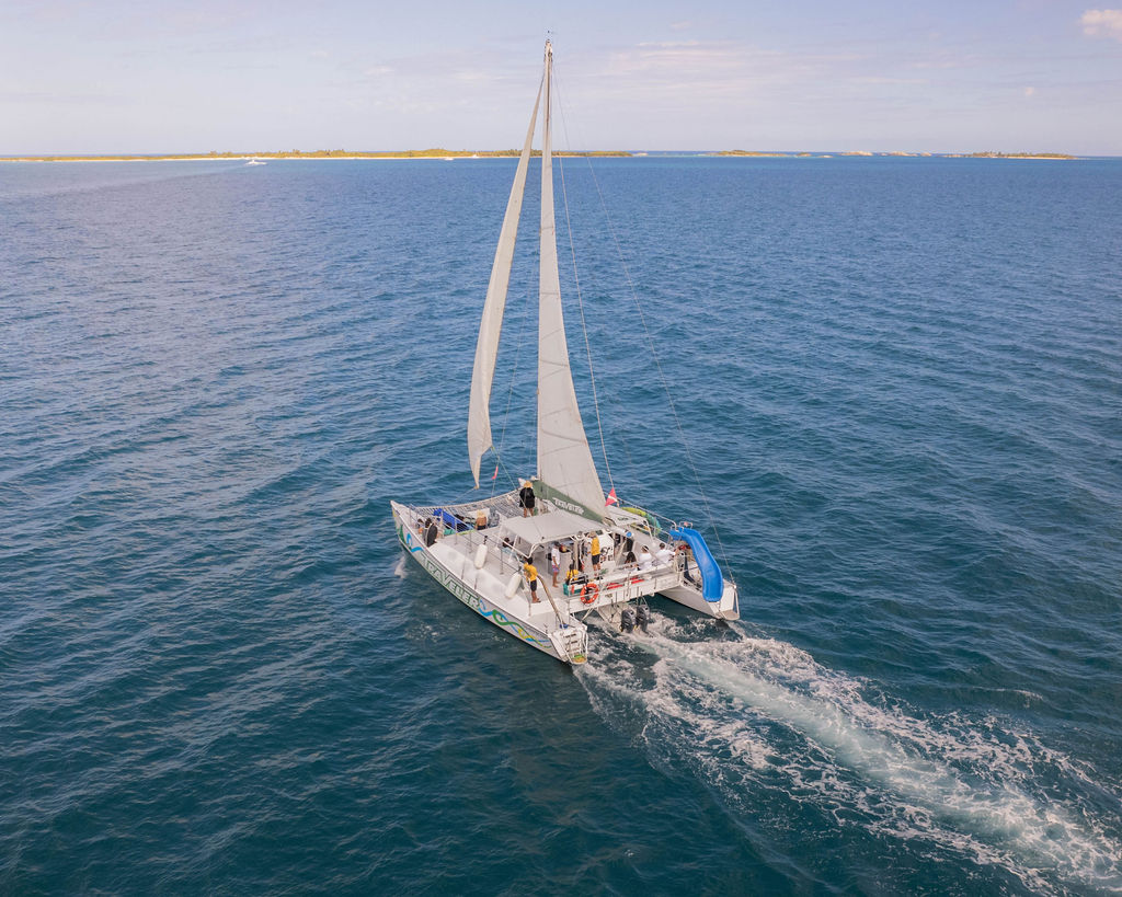 Sailboat with white sails cruising on calm blue sea.