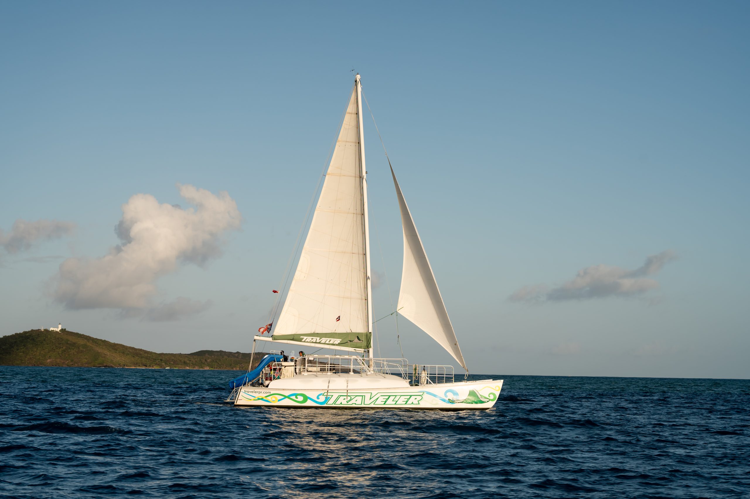 Sailboat in open water with clear skies and distant land.