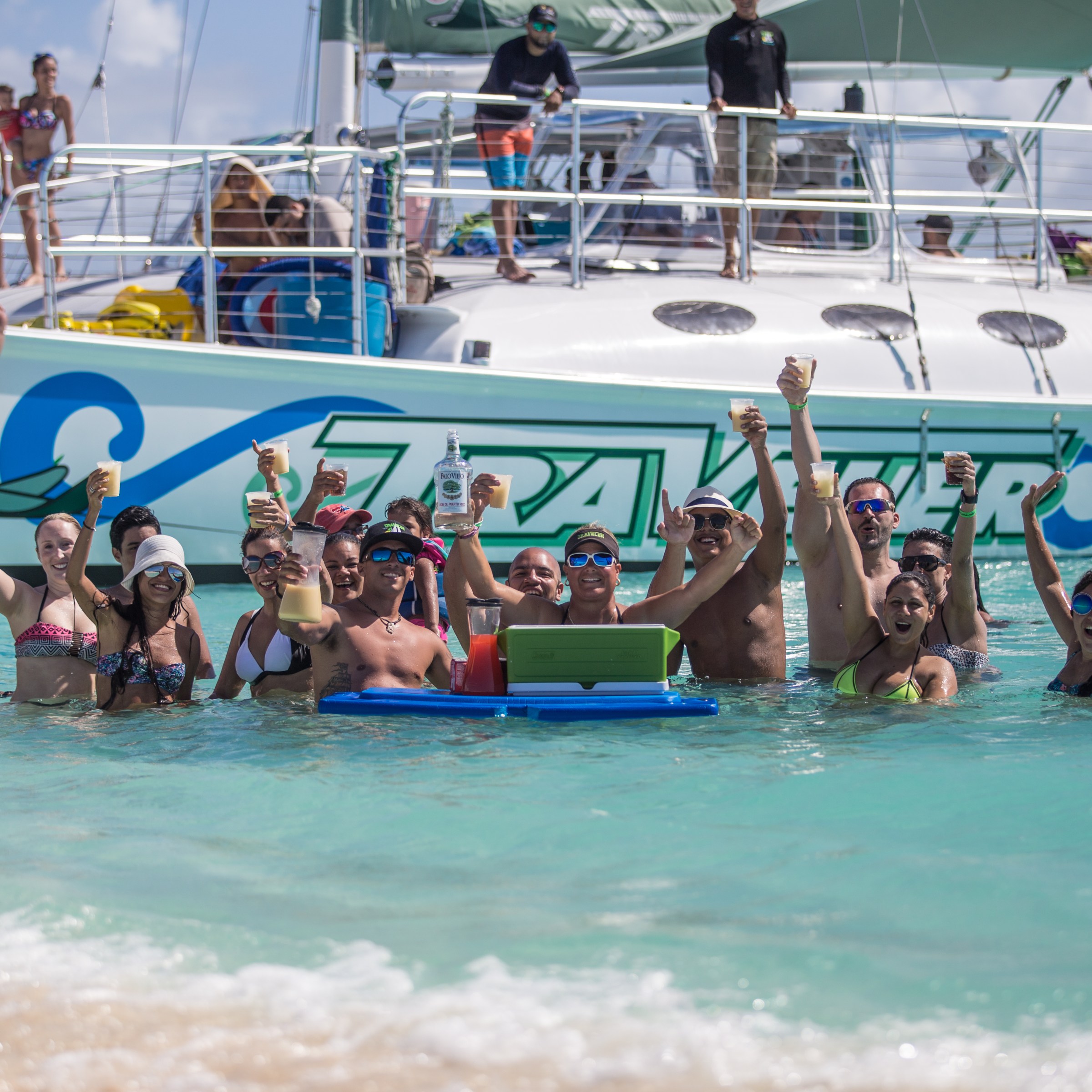 people hanging out near the shore of a beach with a boat